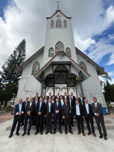 Foto 20. Suasana di dalam Gereja HKBP Balige — interior kayu, langit-langit berkubah, danderetan jendela kaca patri berwarna kuning-hijau yang membingkai salib altar. Foto bersamadiambil seusai pelayanan koor pada Ibadah Minggu, 26 Juli 2026