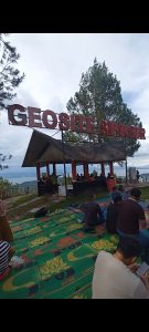 Foto 15. Sebagian rombongan Grup Koor Kaum Bapak HKBP Ressort Slipi berfoto di dek pandang Geopark Sipinsur, Humbang Hasundutan, Sabtu 25 Juli 2026. Di kejauhan tampakhamparan Danau Toba dengan Pulau Sibandang dan kawasan Muara.