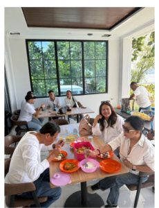 Foto 5. Makan siang di ruang makan Lakeside Haus Balige, Jumat 24 Juli 2026. Jendela besar ruang makan menghadap ke arah pepohonan dan perairan Danau Toba. Tampak pula para ibu pendamping yang membantu melayani konsumsi rombongan sepanjang perjalanan