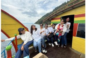 Foto 11. Kegembiraan para ibu pendamping di geladak kapal, dengan permukaan Danau Toba yang berkilau memantulkan cahaya matahari sore di latar belakang.