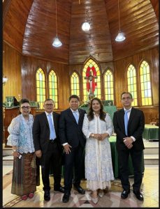 Foto 23. Suasana di dalam Gereja HKBP Balige — interior kayu, langit-langit berkubah, dan deretan jendela kaca patri berwarna kuning-hijau yang membingkai salib altar. Foto bersama diambil seusai pelayanan koor pada Ibadah Minggu, 26 Juli 2026.